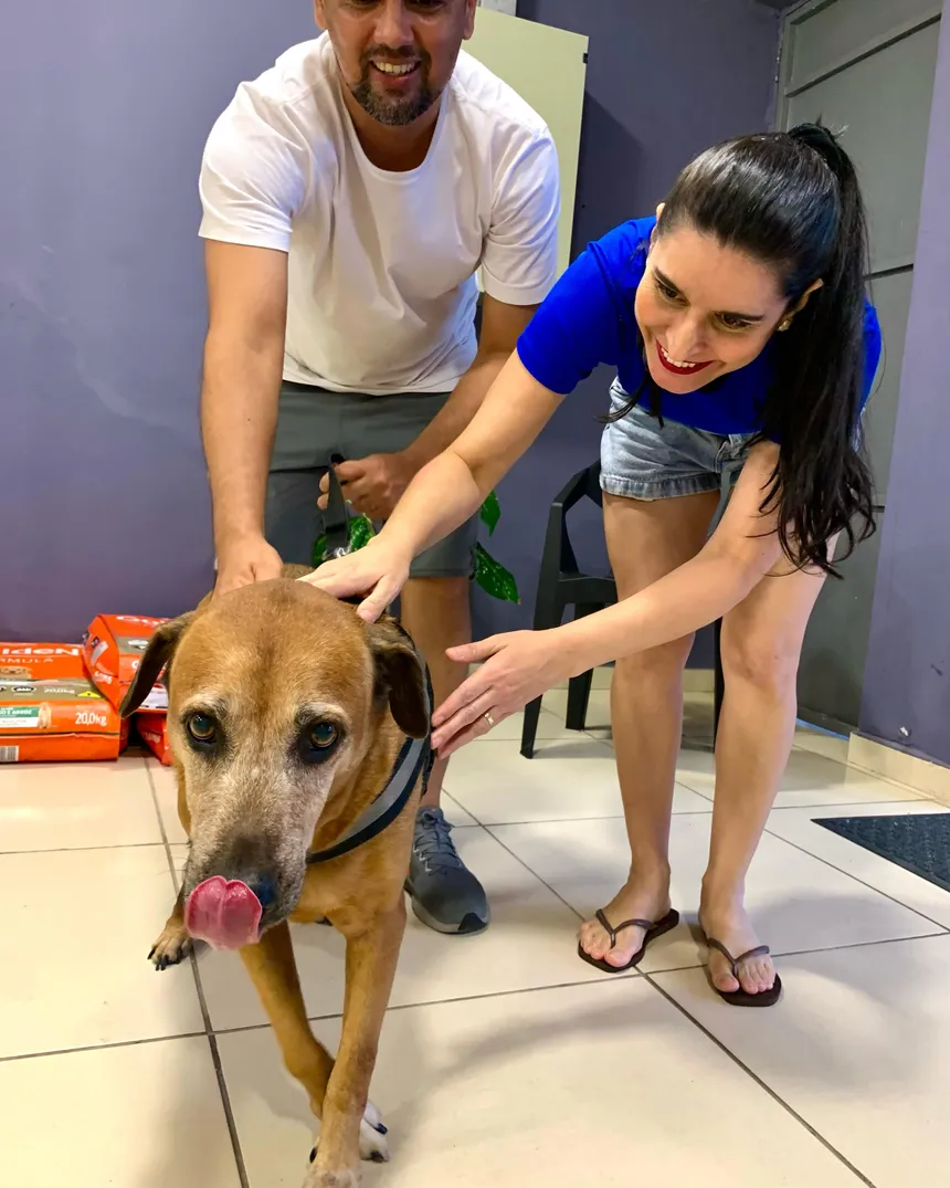 Tutores fazendo carinho no cachorro atendido na clínica